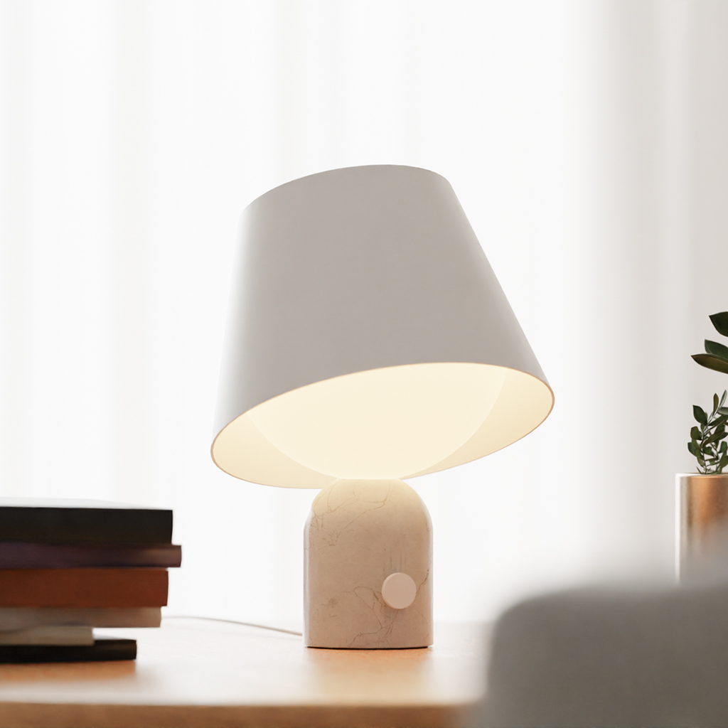 A white table lamp by Koncept, glowing against a white curtain