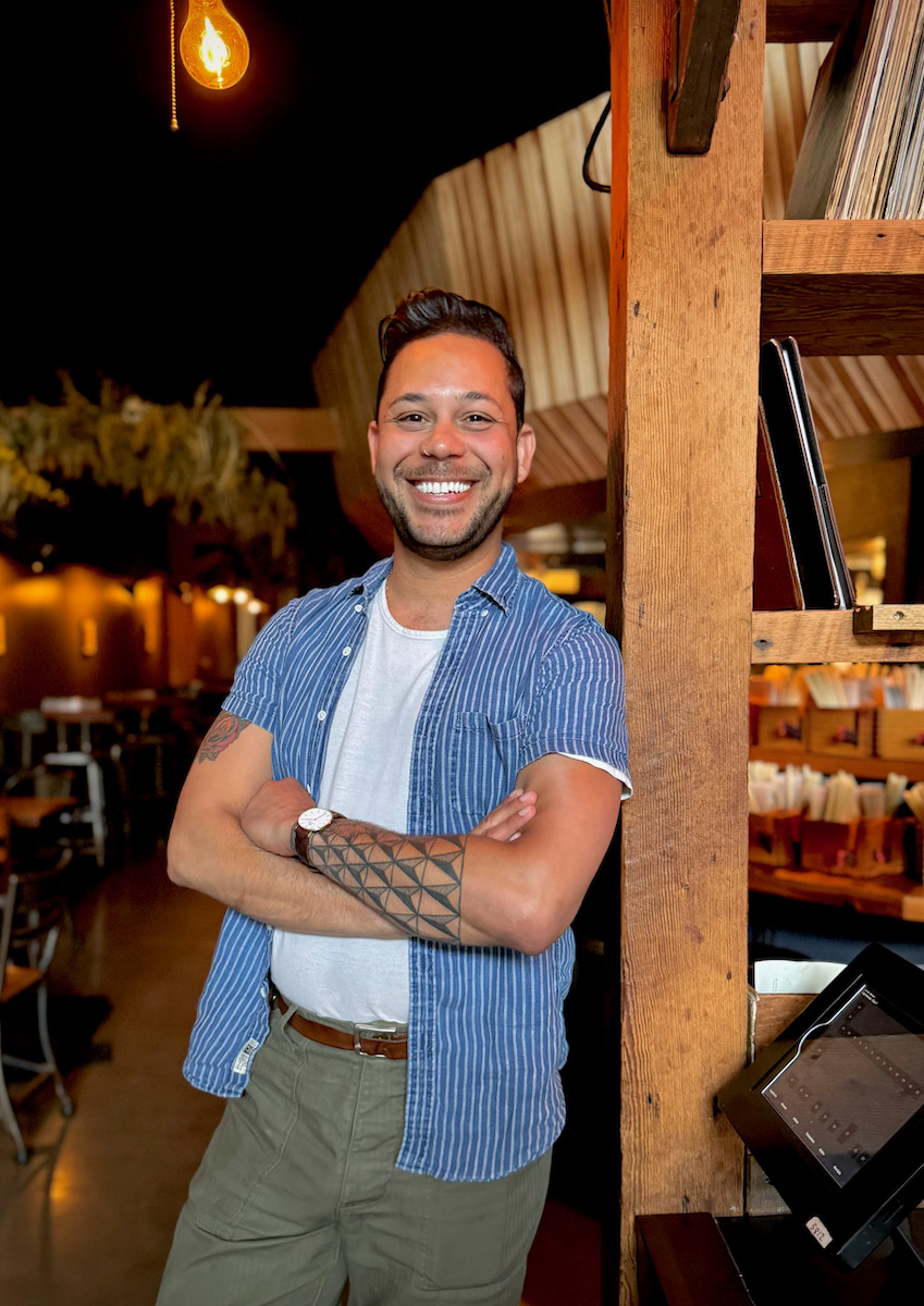 Landon Hayes of ramen shop stands in front of his kitchen, arms crossed