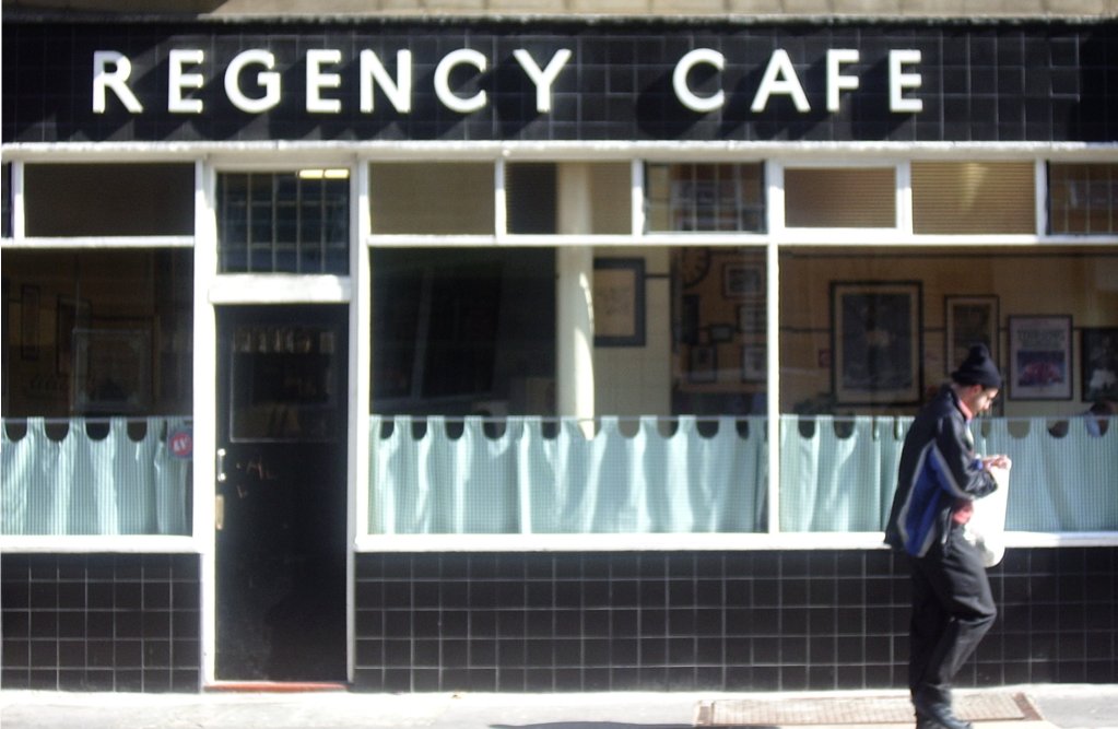 The façade of a London restaurant with a man standing outside of it 