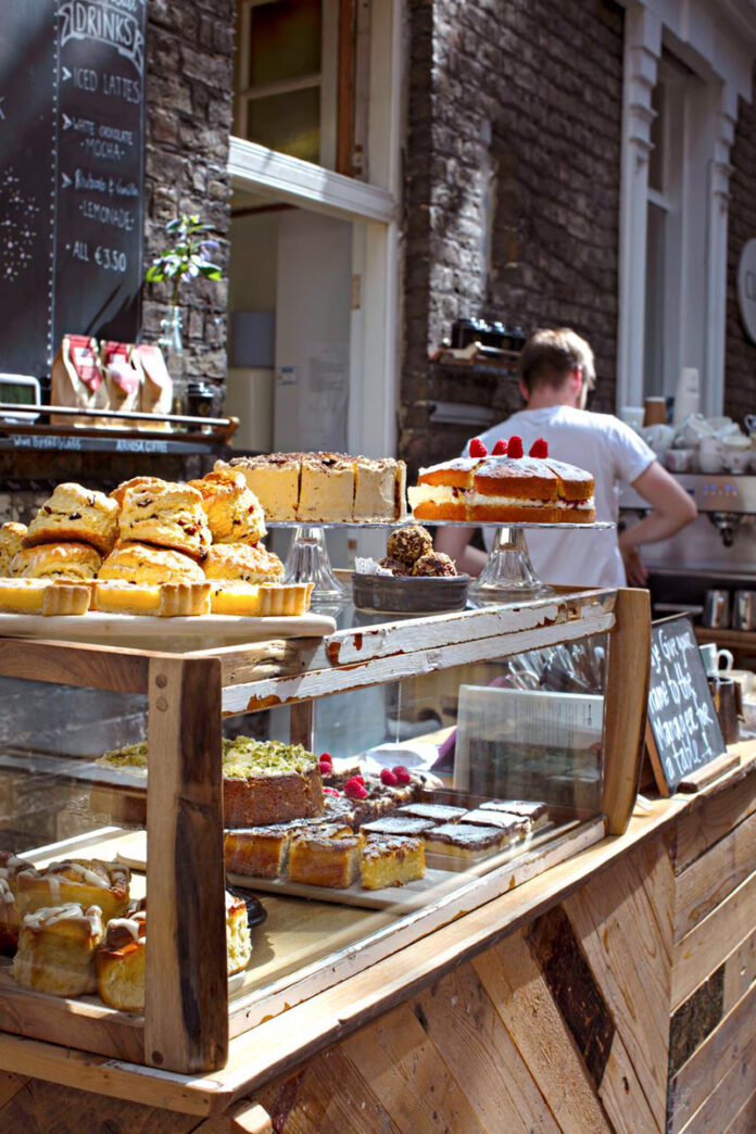 A glass case of multiple pastries outside on a sunny day