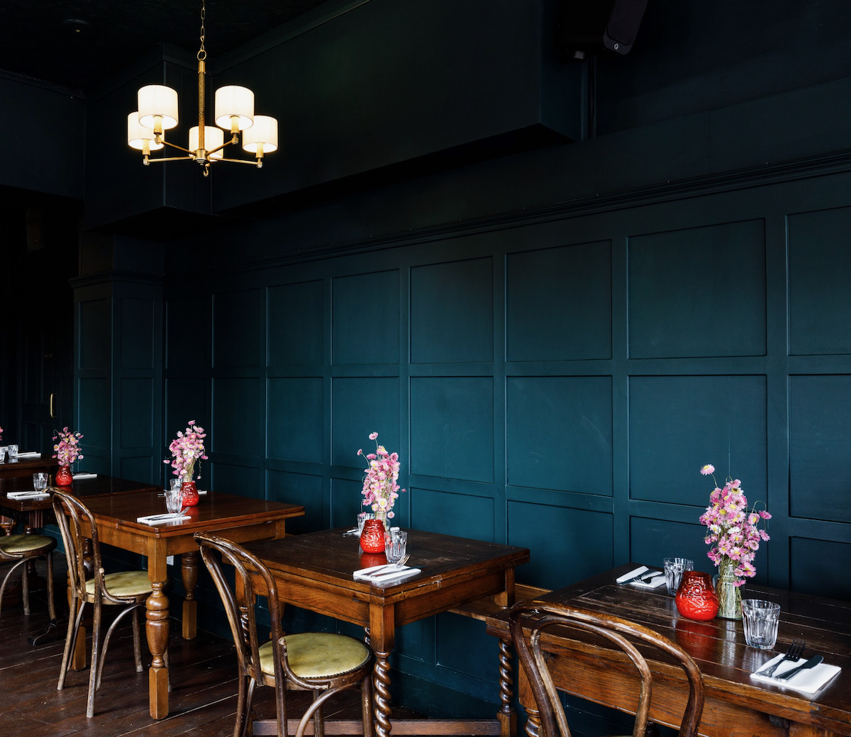 The interior of Tamil Prince, with teal walls and set tables with flowers