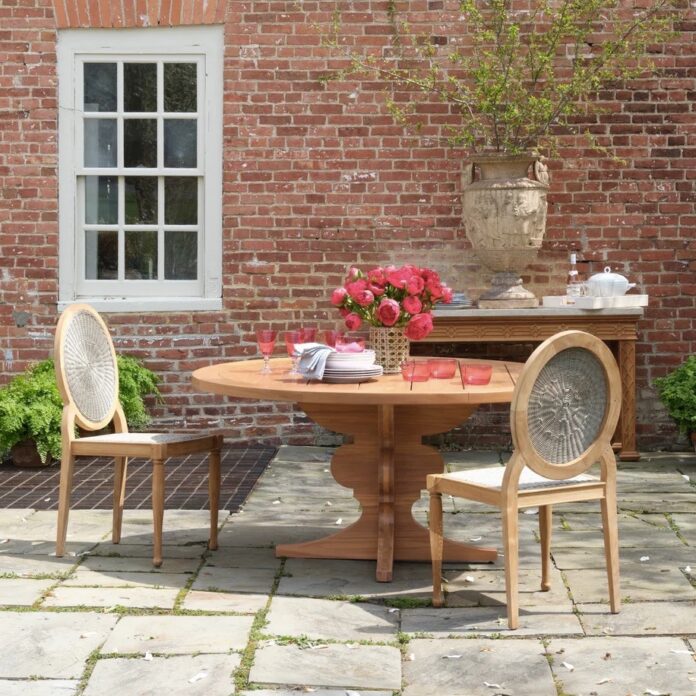 bunny williams outdoor overall TABLE Magazine A Bunny Williams outdoor table with two chairs sitting at it and flowers resting on the brown table.