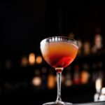 A tall glass sits on a bar with an orange and red hue to represent the Bene Gesserit in Dune Prophecy.