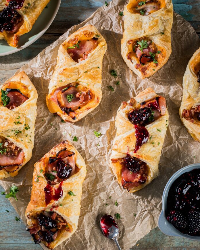 Six Breakfast Pastry Puffs sit on butcher paper as a bit of blackberry topping peaks in from the right side.