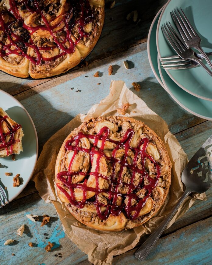 A peanut butter and jelly roll sits on a piece of butcher's paper while another one sits in the upper left hand corner.