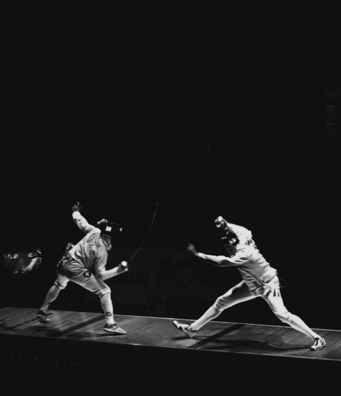 Paris Olympics Pentathlon Watch Party Menu Two people in white suits and black masks fence at the Olympics as a part of the Pentathlon.