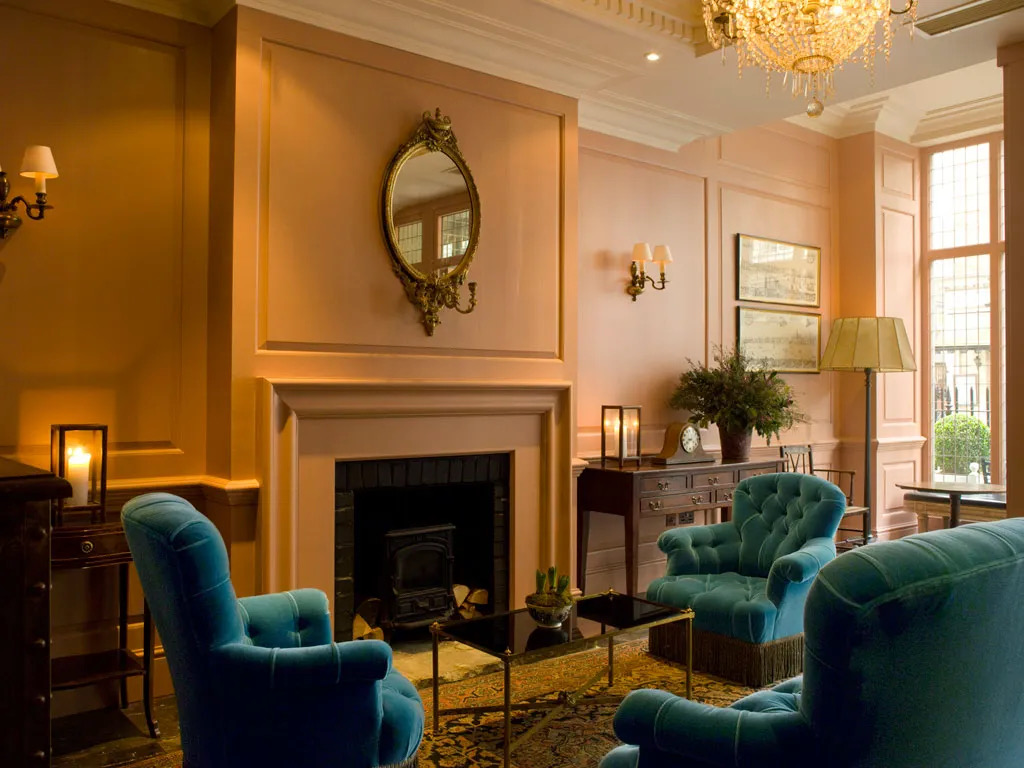 Interior shot of Dean Street townhouse with green velour chairs and a fireplace