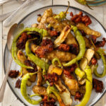 A plate of ozettes, Corbaci peppers, and sausage on a white background