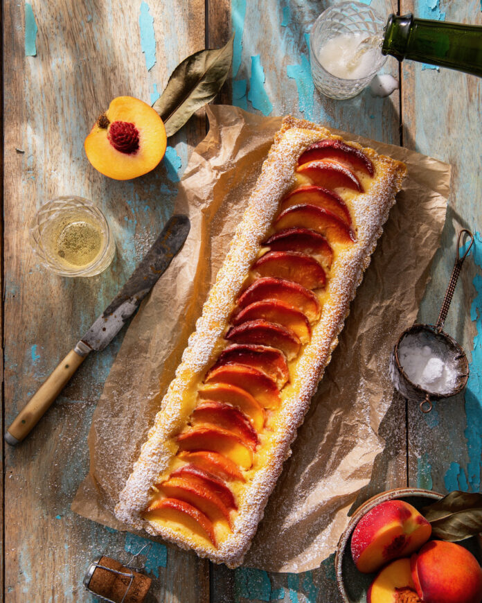 TABLE Magazine Peach Bellini Tart A peach bellini tart on a rustic wooden table