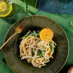 A plate of cacio e pepe on a green background