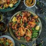 A green curry chicken thigh dish on a black background