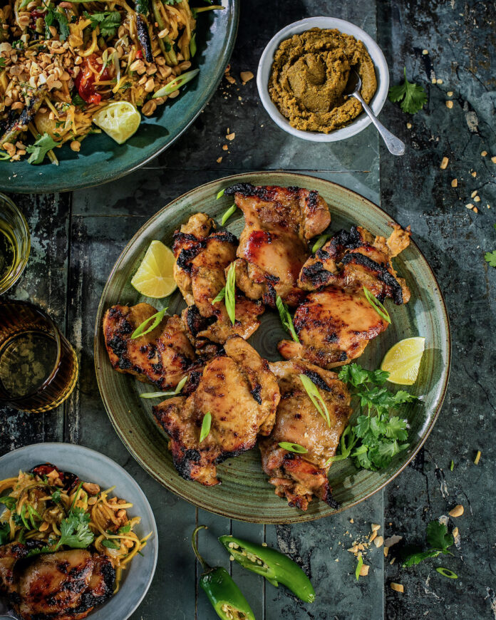 A green curry chicken thigh dish on a black background