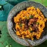 A plate of risotto milanese on a green background