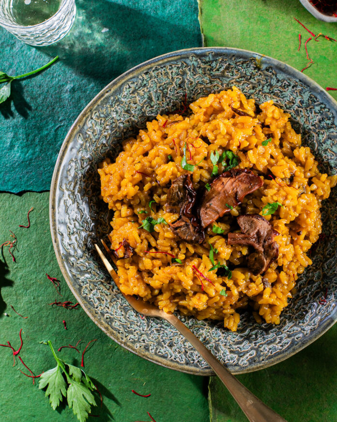 A plate of risotto milanese on a green background