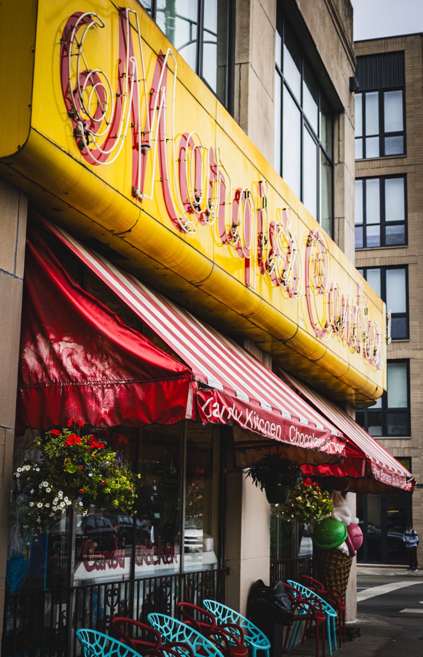 The outside of Margie's Candies sits in downtown Chicago with a yellow sign and red awning. 
