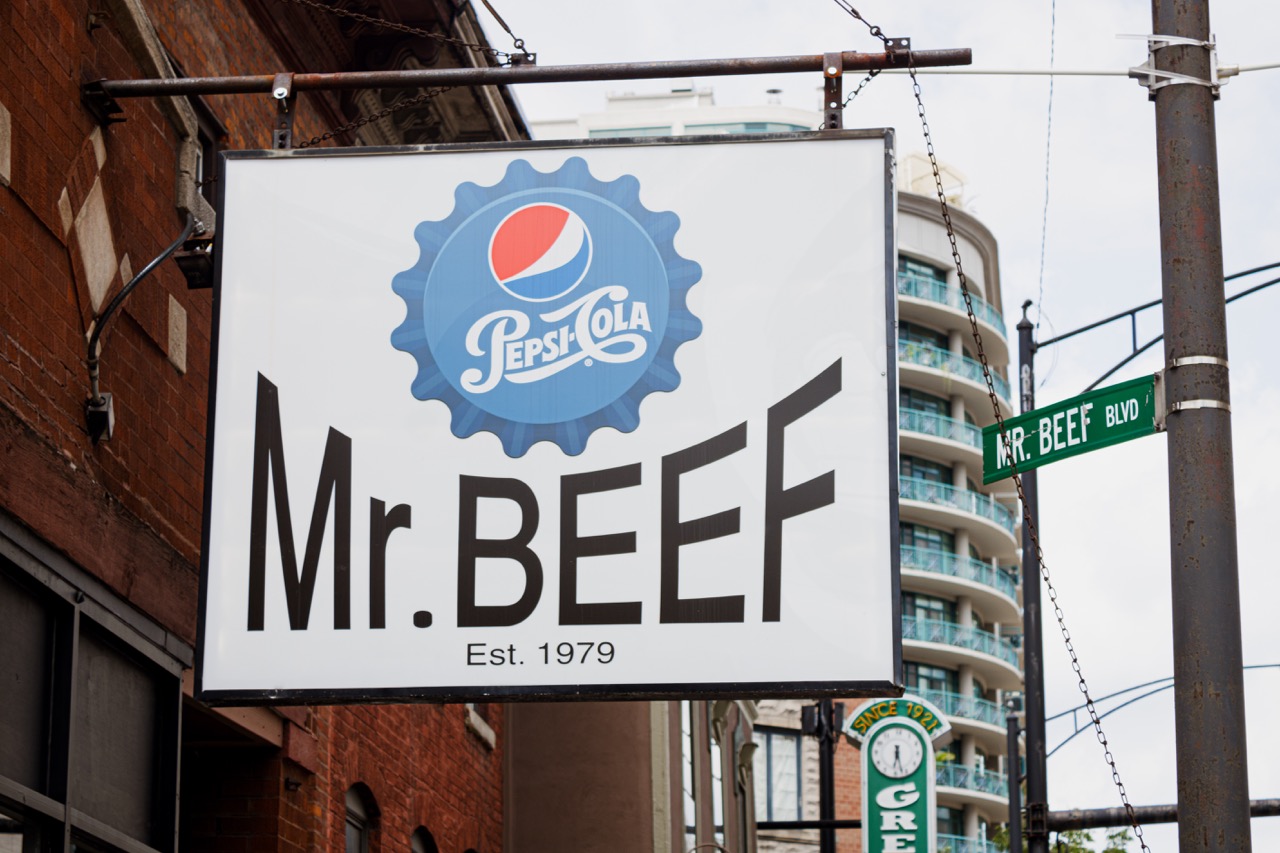 The Mr. Beef sign hands beside a Mr.Beef street sign.