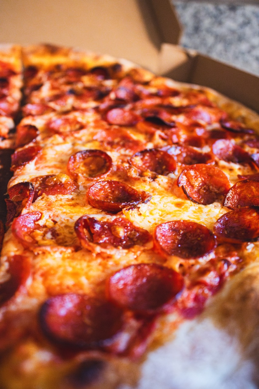 A crisp pepperoni pizza sits in a box on a counter top. 