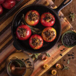 Four baked apples stuffed with sausage plated rustically on a wood background