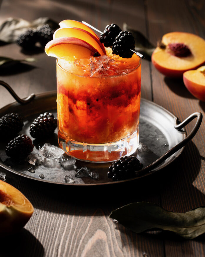A craft bourbon smash cocktail on a black background