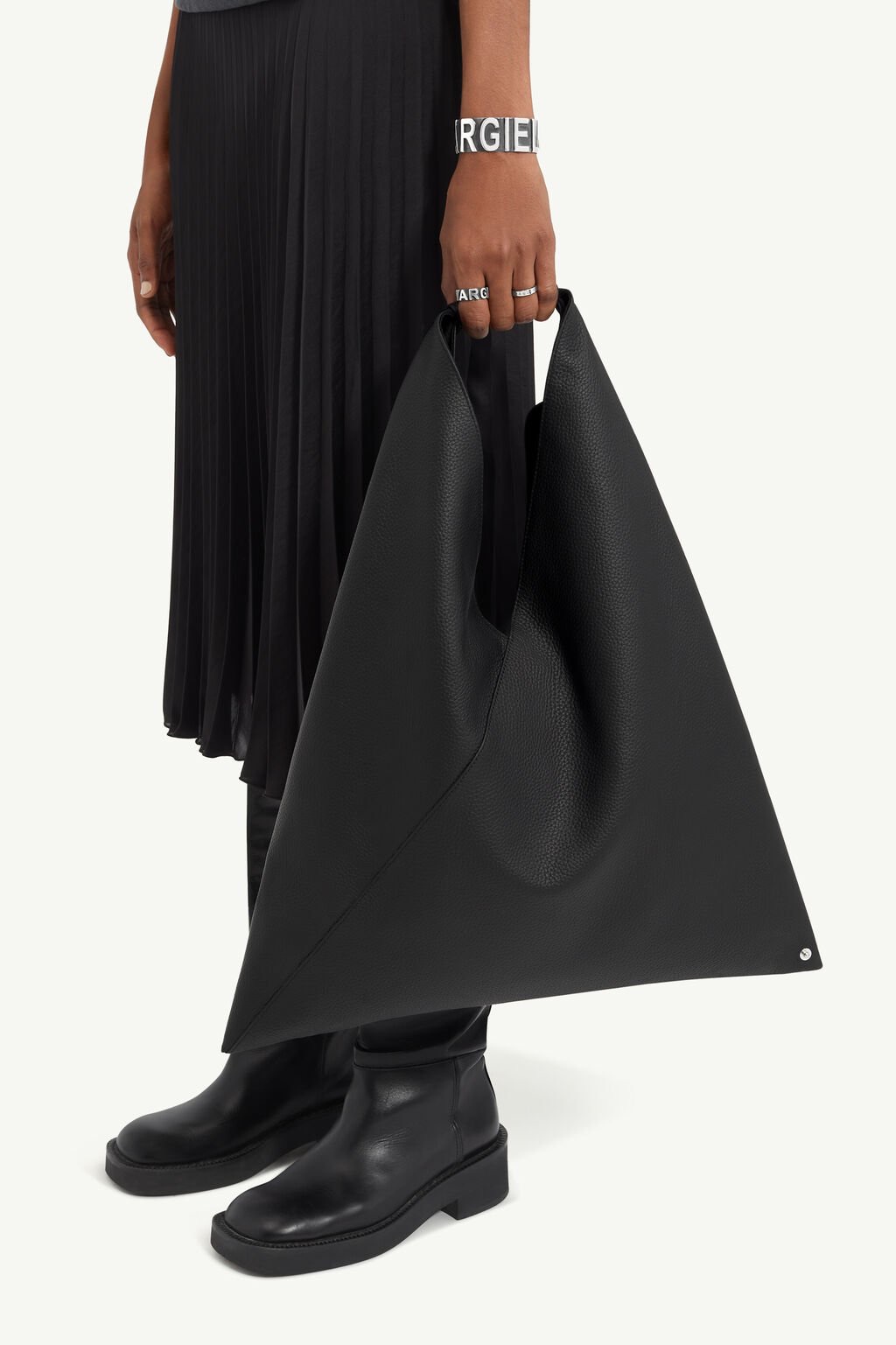 A person in a black skirt holds a black bag in a triangle shape.