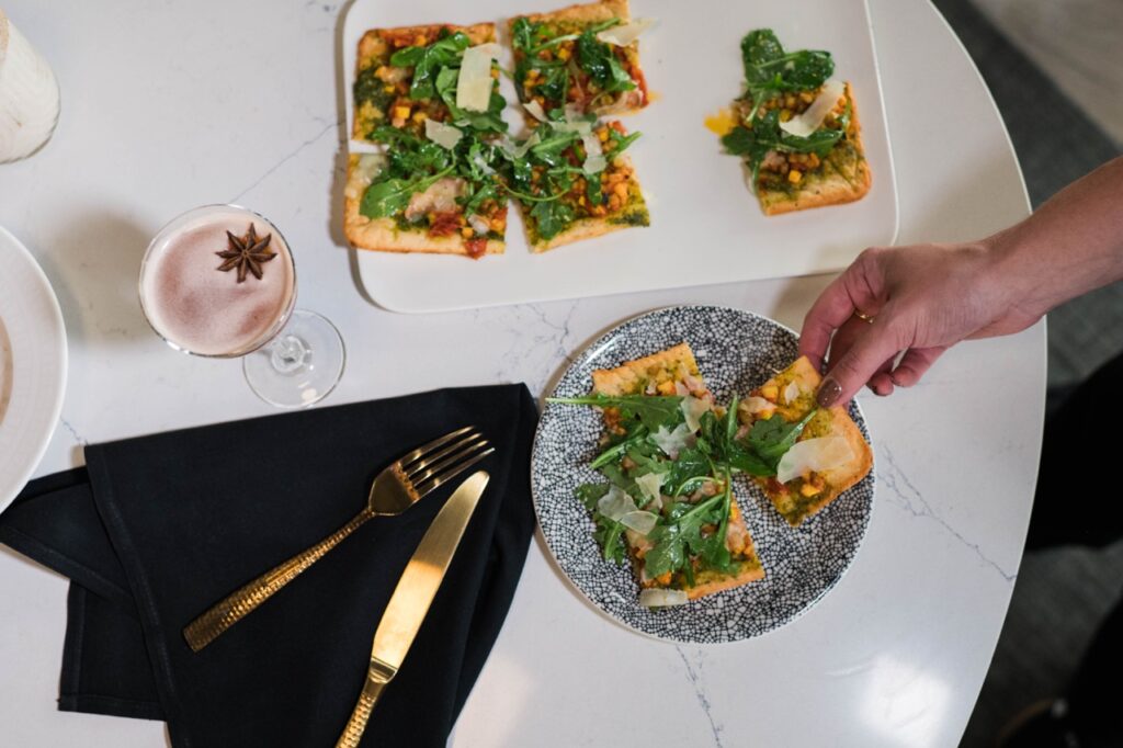A white table with a flatbread pizza on top cut into slices.