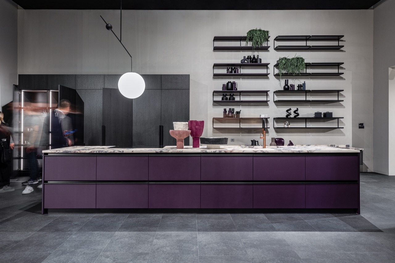 A long purple counter with a marble white top is in a kitchen with a round light hanging above it.
