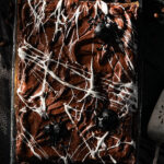 A Halloween brownie in a sheet pan drizzled to look like a spider web.