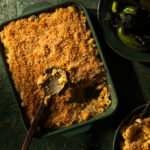 Baked mac and cheese in a pan on a dark green background