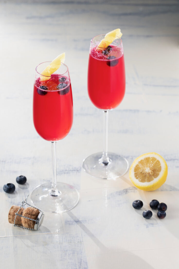 Two glasses of a red French 75 on a white background