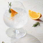 An Italian gin and tonic with an orange slice on a white background