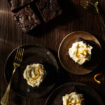 Three brownies frosted with luxardo buttercream frosting and topped with orange zest