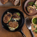 A pear grilled cheese sandwich set on a rustic table with slices of bread beside it