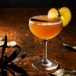 A Thankgiving dinner table set with a mocktail garnished with apple