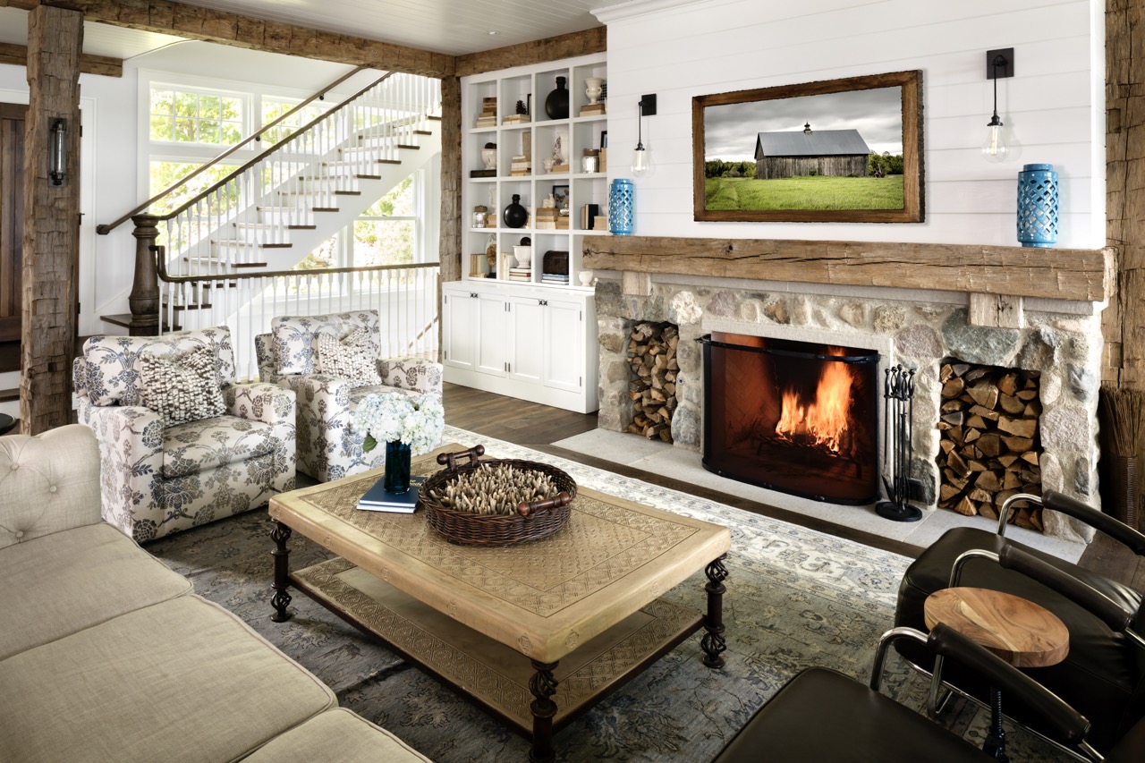 A living area contains a stone fireplace, beige couch and table along with white walls and cabinets. 