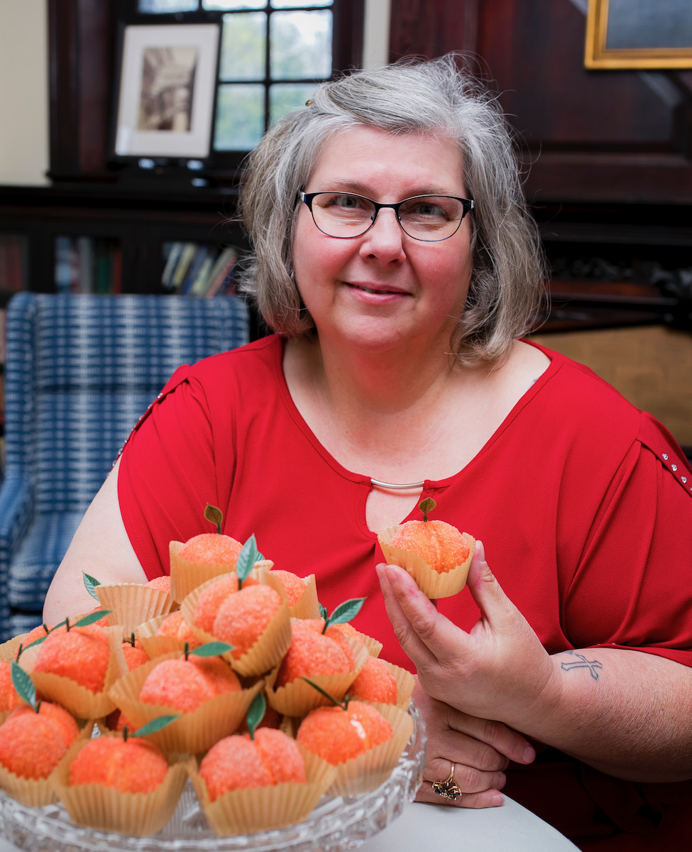 Lori Willis, a woman with white hair in a red shirt, sits in front of her peach cookies
