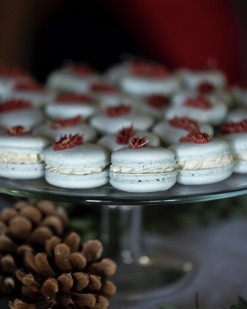 A side view of blue corn macarons with a cream in between the cookies and a red floral decor top.