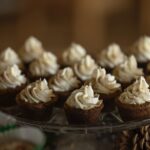 On a glass platter sits a group of cookie cups with swirls of white icing on top.