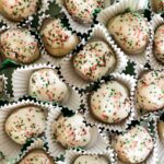 Small Lemon Ricotta Cookies sit in a pile, each wrapped in a small cupcake wrapper.
