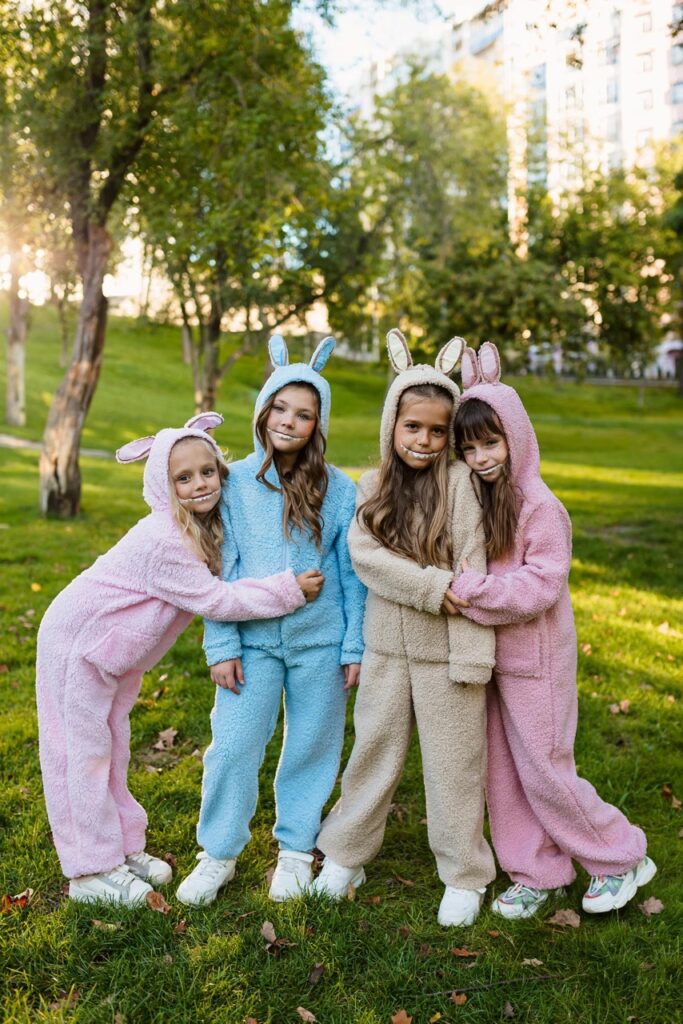 Four little girls in pink, blue, and beige Labubu costumes standing outside.