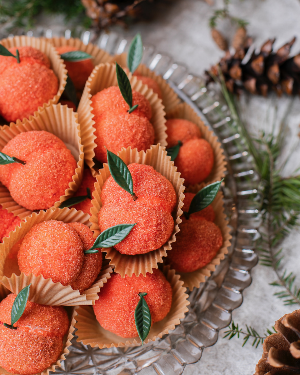 Orange cookies that look like little peaches on a piece of glassware