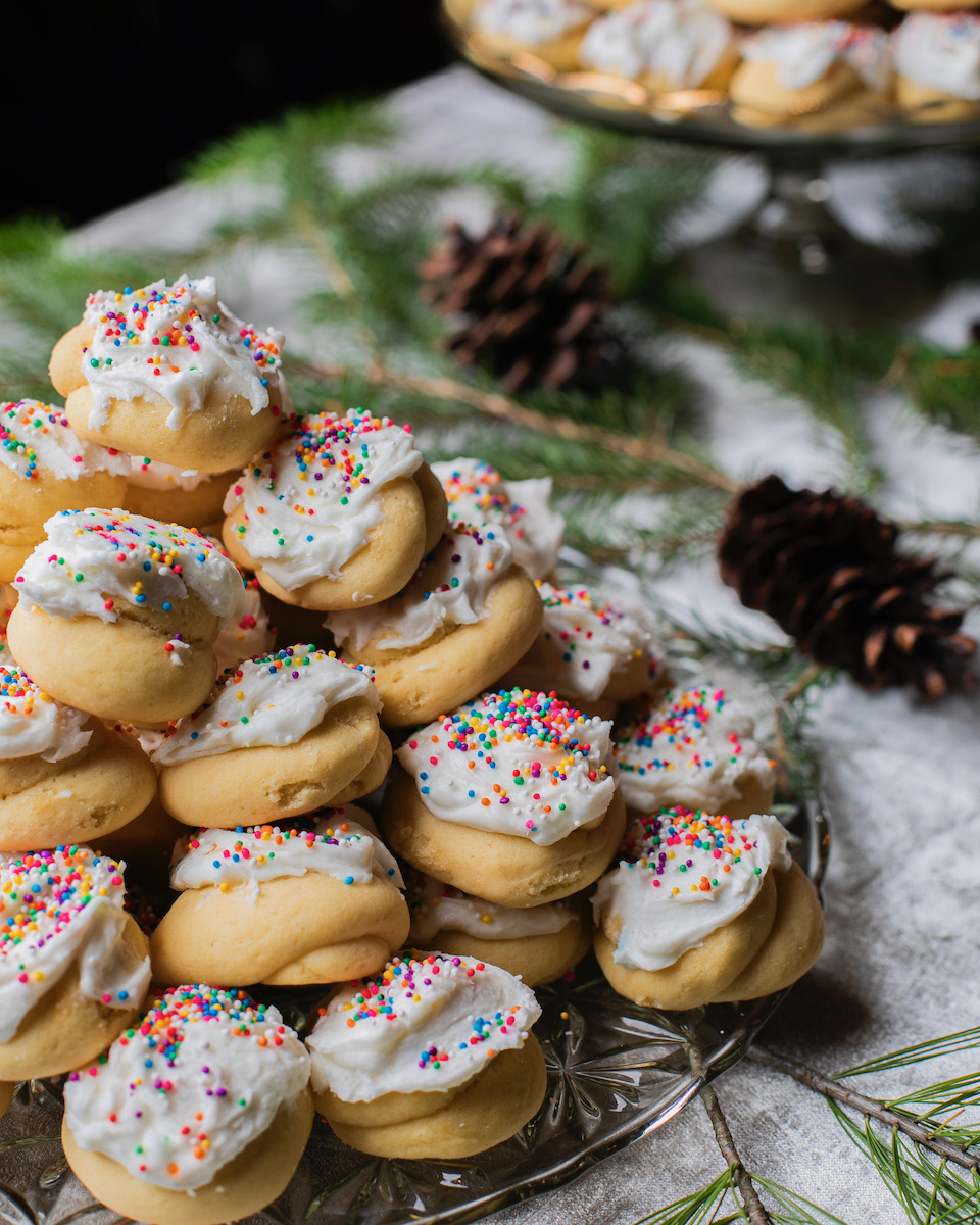 Italian Wedding Cookies stacked on top of each other and frosted with non-pareils