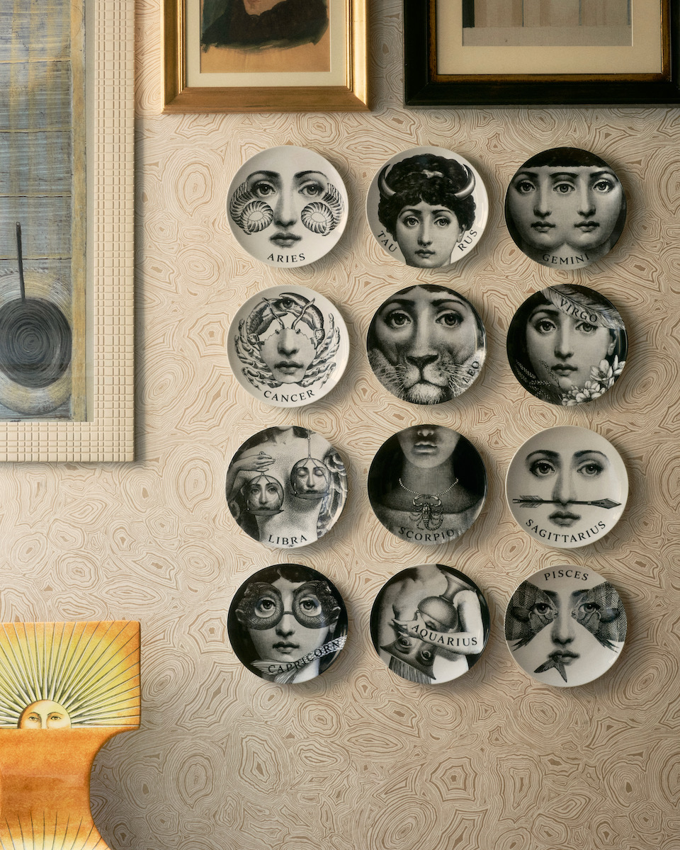 Plates by Fornasetti hung on a wall with faces on them 