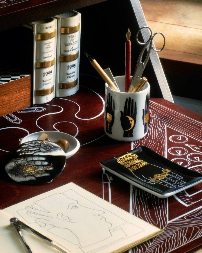 Holiday Gifts alla Fornasetti Porcelain objects on a red table top, staged with other design items