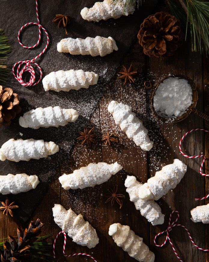 TABLE Magazine Lady Locks Small white cookies, lady locks, on a dark brown background