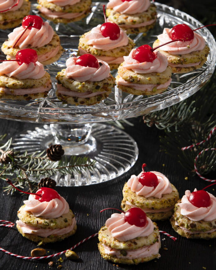 Pistachio Sandwich Cherry Cookies A plate of pistachio sandwich cherry cookies on a piece of glassware