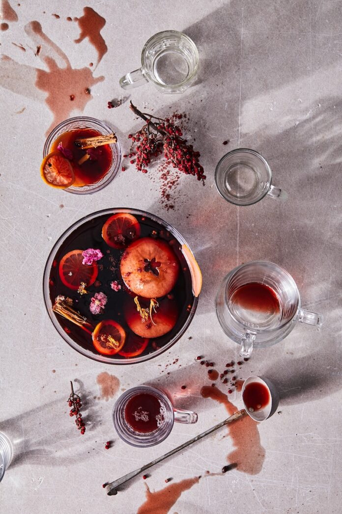 A glass of mulled wine on a white background, garnished with fruit