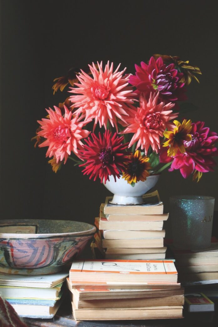 Best Gardening Books A pot of red flowers on top of a stack of gardening books