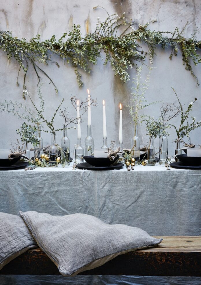 South Africa Christmas A table set with candles and sprigs of Christmas plants, surrounded by grey throw pillows