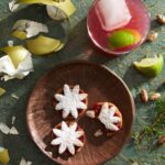 Chrisma Politan Cocktail with a twist of citrus and a touch of elegance, garnished with fresh cranberries and a sprig of rosemary.