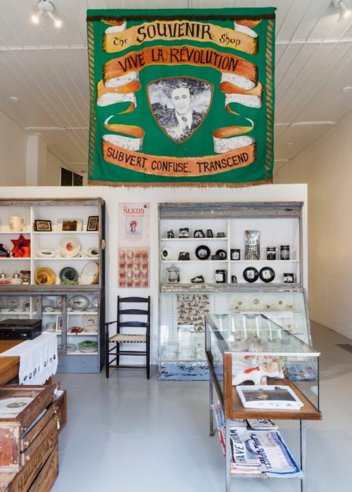 Mattress Factory Museum gift Shop TABLE Magazine The inside of the Mattress Factory Gift Shop for the museum with white shelves and a green banner.
